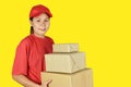 Delivery woman holding boxes on yellow background. Royalty Free Stock Photo