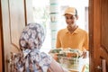 Deliveryman carrying vegetable basket standing in front of door