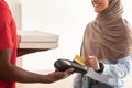 Deliveryman holding POS machine, muslim woman paying with card Royalty Free Stock Photo