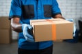 Deliveryman, latex gloved, holds smartphone and a cardboard box for delivery