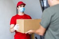 Postman, deliveryman wearing mask carry small box deliver to customer in front of door at home. Man wearing mask prevent covid19, Royalty Free Stock Photo