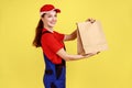 Deliverywoman giving paper parcel to client, fast delivery service, looking at camera with smile. Royalty Free Stock Photo