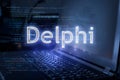 Delphi inscription against laptop and code background. Learn programming language, computer courses, training