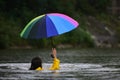 Deluge flood concept. Rainy flood day. Funny woman in raincoat hold umbrella in water. Girl in rain with umbrella in