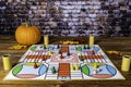 Playing Parcheesi on a fall day with orange pumpkin and autumn leaves