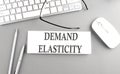 DEMAND ELASTICITY text on paper with keyboard on grey background