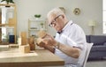 Demented senior man with Alzheimer& x27;s disease sitting at table and playing with wooden cubes