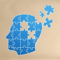 Dementia concept. Drawing of blue head shaped jigsaw puzzle with missing pieces on beige background