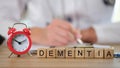 Dementia word collected of wooden cubes in row and alarm clock