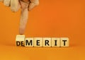 Demerit or merit symbol. Businessman turns wooden cubes and changes the concept word Demerit to Merit. Beautiful orange table Royalty Free Stock Photo