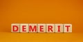 Demerit symbol. The concept word Demerit on wooden cubes. Beautiful orange table, orange background, copy space. Business and Royalty Free Stock Photo