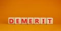 Demerit symbol. The concept word Demerit on wooden cubes. Beautiful orange table, orange background, copy space. Business and
