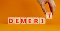 Demerit symbol. The concept word Demerit on wooden cubes. Beautiful orange table, orange background, copy space. Businessman hand Royalty Free Stock Photo
