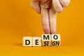 Demo and design symbol. Businessman hand turns cubes and changes the word `design` to `demo`. Beautiful orange background. Royalty Free Stock Photo