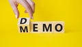 Demo and Memo symbol. Businessman hand turns wooden cube and changes word Memo to Demo. Beautiful yellow background. Business and