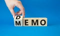 Demo and Memo symbol. Businessman hand turns wooden cube and changes word Memo to Demo. Beautiful blue background. Business and