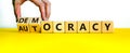 Democracy or autocracy symbol. Businessman turns wooden cubes and changes the word autocracy to democracy. Beautiful white