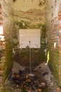 A demolished house with an inexplicable stream of water coming out of the wall with tiles on brick walls