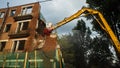 Demolition of a brick building with excavator mechanical arm. Destruction of dilapidated housing. Heavy machinery Royalty Free Stock Photo