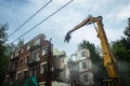 Demolition of a brick building with excavator mechanical arm. Destruction of dilapidated housing. Heavy machinery Royalty Free Stock Photo