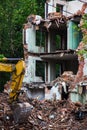 Demolition of a brick building with excavator mechanical arm. Destruction of dilapidated housing. Heavy machinery Royalty Free Stock Photo