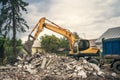 Demolition of building by industrial excavator. Demolished broken walls and roof of old house, pile of industrial Royalty Free Stock Photo