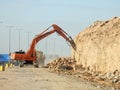 demolition hydraulic crawler excavator removing prats from a hill or a mountain on the roadside to develop and widen the highway