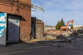 Demolition of obsolete dilapidated buildings. A big orange excavator destroys an old factory