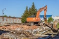 Demolition of obsolete dilapidated buildings. A large orange excavator stands on the rubble of a demolished building Royalty Free Stock Photo