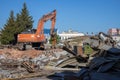 Demolition of obsolete dilapidated buildings. A large orange excavator stands on the rubble of a demolished building Royalty Free Stock Photo