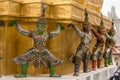 Demon guardian yaksha supporting golden pagoda at Wat Phra Kaew or the temple of the Emerald Buddha within the grounds of the