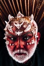 Demon head with thorns on face appearing from darkness, underworld concept. Evil monster with red skin wearing metallic Royalty Free Stock Photo