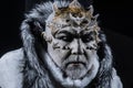 Demon with horns on head and shinning golden skin wearing white fur coat on black background. Evil winter deity