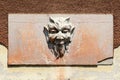 Demon like vintage concrete statue mounted on cracked plate on side of abandoned movie theater building