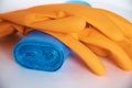 Demonstration of kitchen care products: a roll of garbage bags and orange household gloves. Close-up.