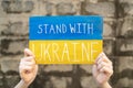 Demonstrator holding `Stand with Ukraine` placard