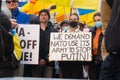 Demonstrators with yellow and blue Ukraine flags and anti-war signs near Russian consulate