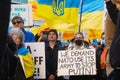 Demonstrators with yellow and blue Ukraine flags and anti-war signs near Russian consulate