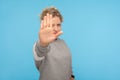 Denial, rejection concept. Young woman with short hair in sweatshirt showing stop gesture, no sign