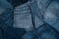 Denim background. Pile of blue jeans. Variety of casual trousers and clothes. Top view to stack of jeans denim