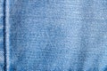 Denim background texture. Close-up of details of empty light blue jeans fabric jean surface with dark blue vertical seam on left Royalty Free Stock Photo