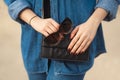 Denim outfit fashion details. Stylish woman with red glitter manicure in navy jeans holding sunglasses and leather small cross bod Royalty Free Stock Photo