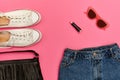 Denim shorts, white sneakers, black handbag, lipstick and glasses. Bright pink background. Fashionable concept