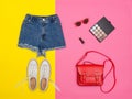 Denim shorts, white sneakers, red handbag. Bright yellow background. Fashionable concept Royalty Free Stock Photo