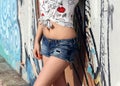 Denim shorts worn by the girl standing near the wall with graffiti