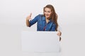 Denim style portrait of teen girl on the floor holding white blank advertising board banner, over white background Royalty Free Stock Photo