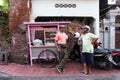 DENPASAR/BALI-APRIL 20 2019: a street meatball seller uses a pink cart and wears a pink shirt chatting with his buyers on the