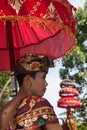 Young man in ethnic Balinese costumes with traditional umbrellas tedung