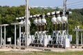 Dense array of electrical equipment at local power plant with metal support for ceramic and glass insulators connected with