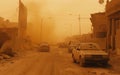 A dense dust storm descends upon a desert town, reducing visibility and coating the urban landscape in a gritty layer.